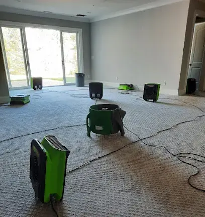 Air movers and a dehumidifier drying carpet in a Wake Forest room