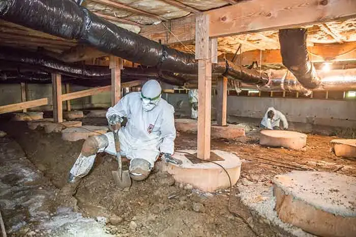Crew member in protective gear working in a Wake Forest crawl space